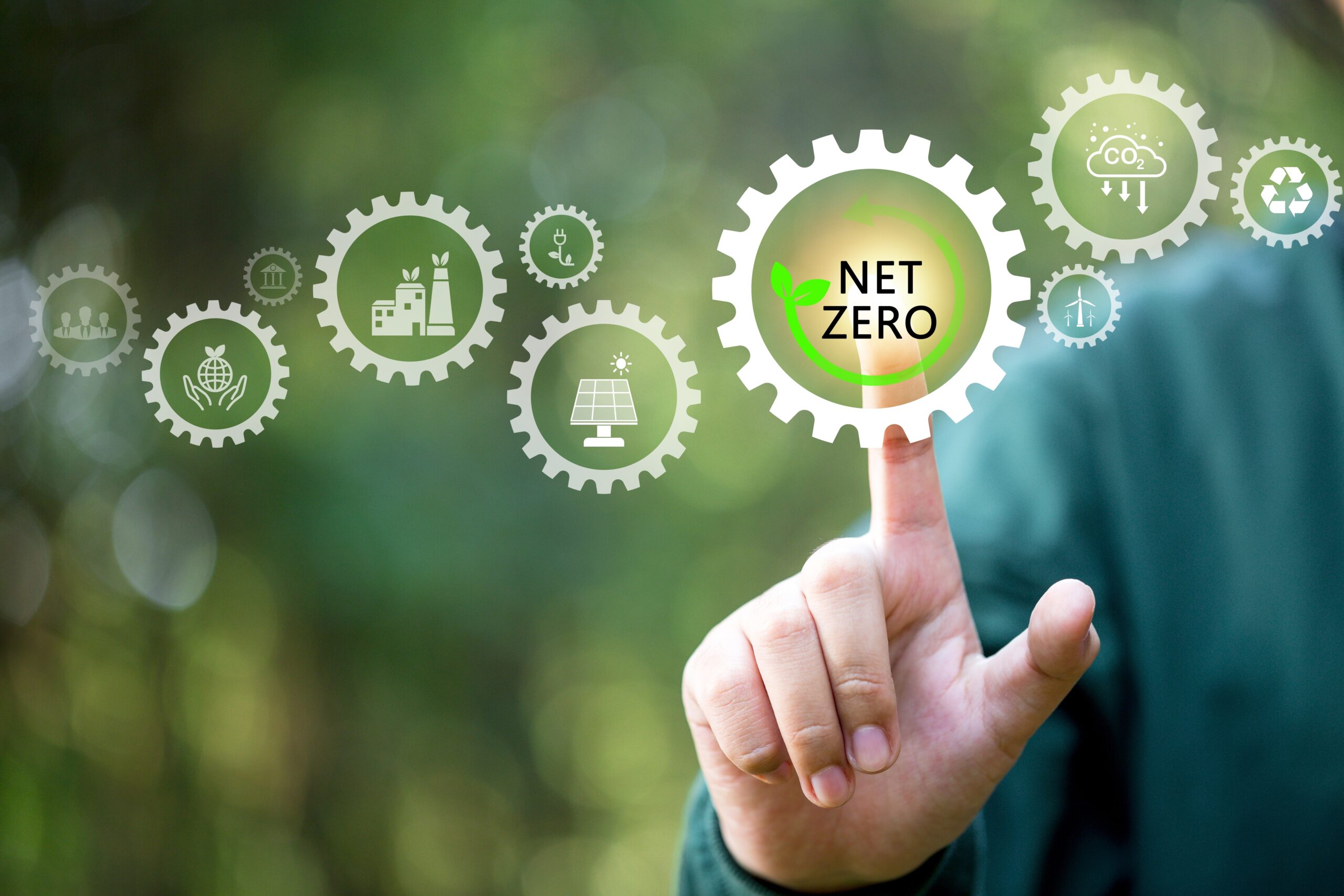 Interactive graphic of interconnected gears with a central gear labelled 'NET ZERO' highlighted by a human finger, symbolizing the engagement with sustainability and emission reduction goals.
